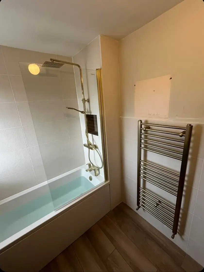 Finished bathroom with glass shower screen, gold fixtures and heated towel rail