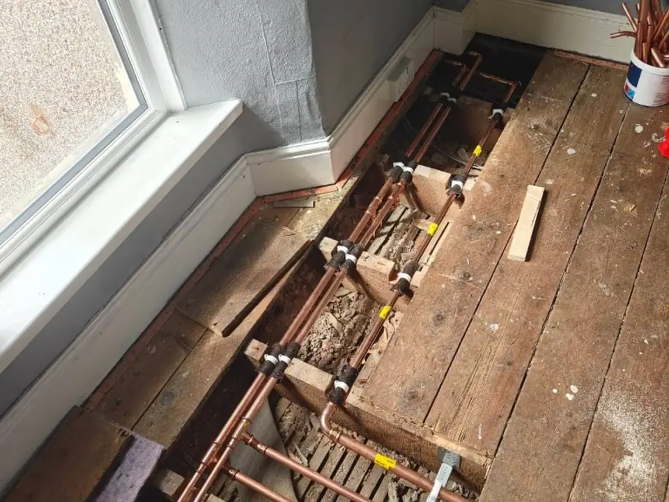 Copper heating pipework run under lifted floorboards on a job